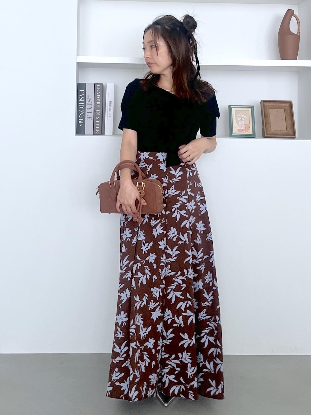 シルバー系のパンプス、ブラウン系のボストンバッグ、ブラウン系のスカートを着用したレディースの夏コーディネートの1枚目の写真