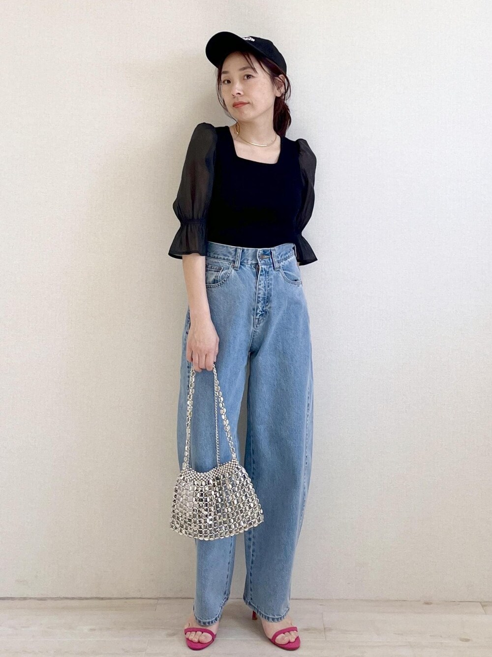 ブラック系のニット/セーター、ブルー系のデニムパンツ、シルバー系のショルダーバッグを着用したレディースの春コーディネートの1枚目の写真