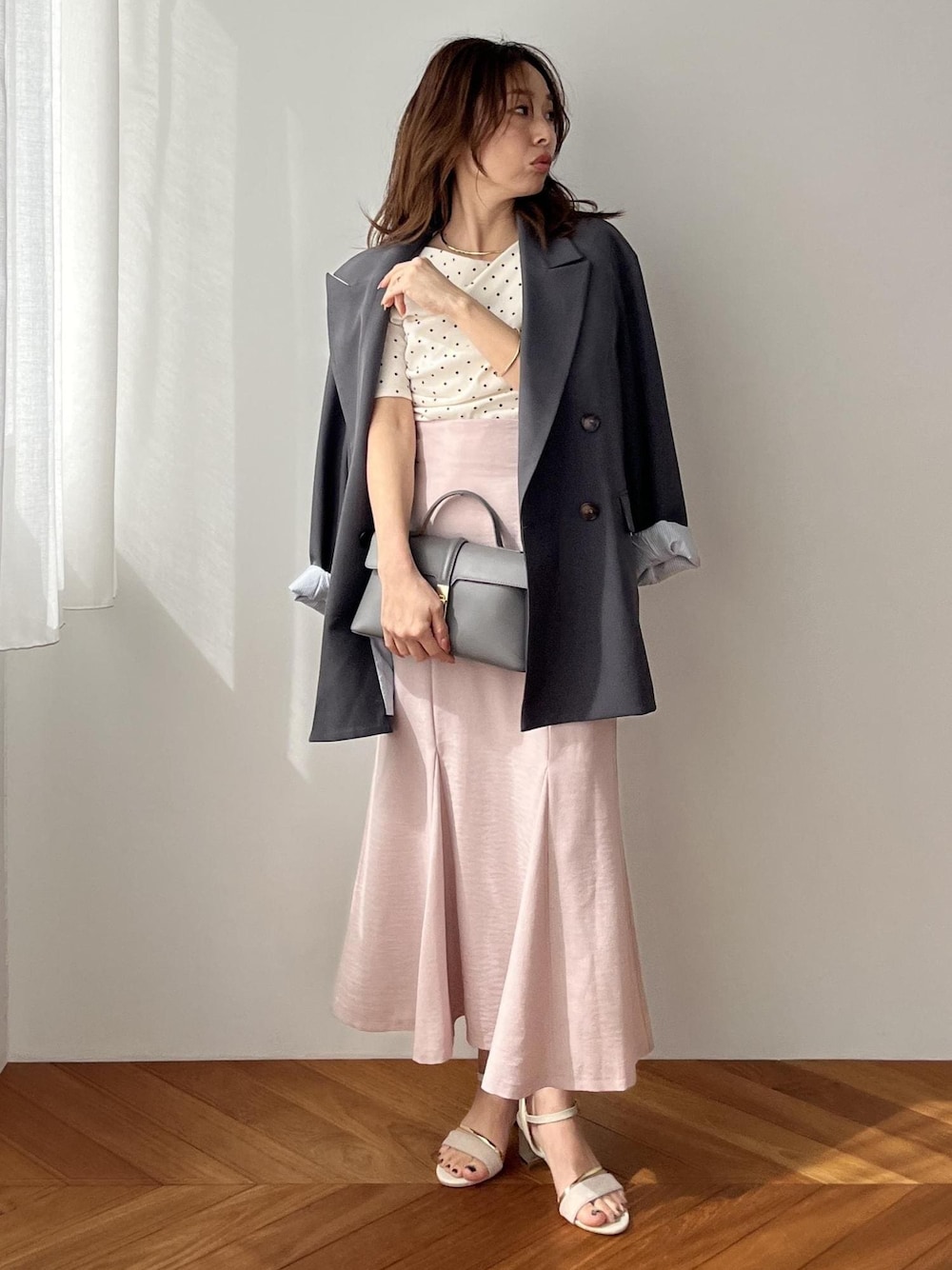 グレー系のショルダーバッグ、グレー系のテーラードジャケット、ピンク系のスカートを着用したレディースの春コーディネートの1枚目の写真