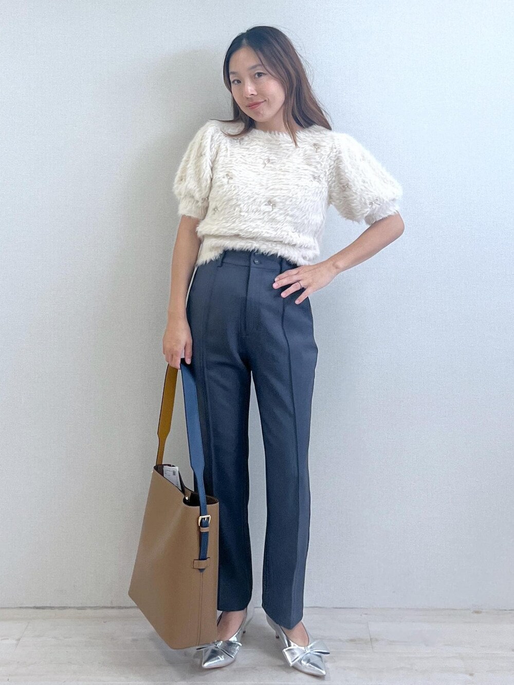 シルバー系のパンプス、イエロー系のショルダーバッグ、ホワイト系のニット/セーターを着用したレディースの秋コーディネートの1枚目の写真