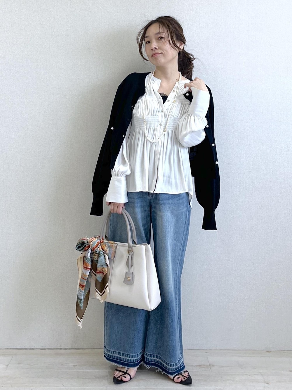 ブラック系のキャミソール、ブルー系のデニムパンツ、ブラック系のカーディガン/ボレロを着用したレディースの春コーディネートの1枚目の写真