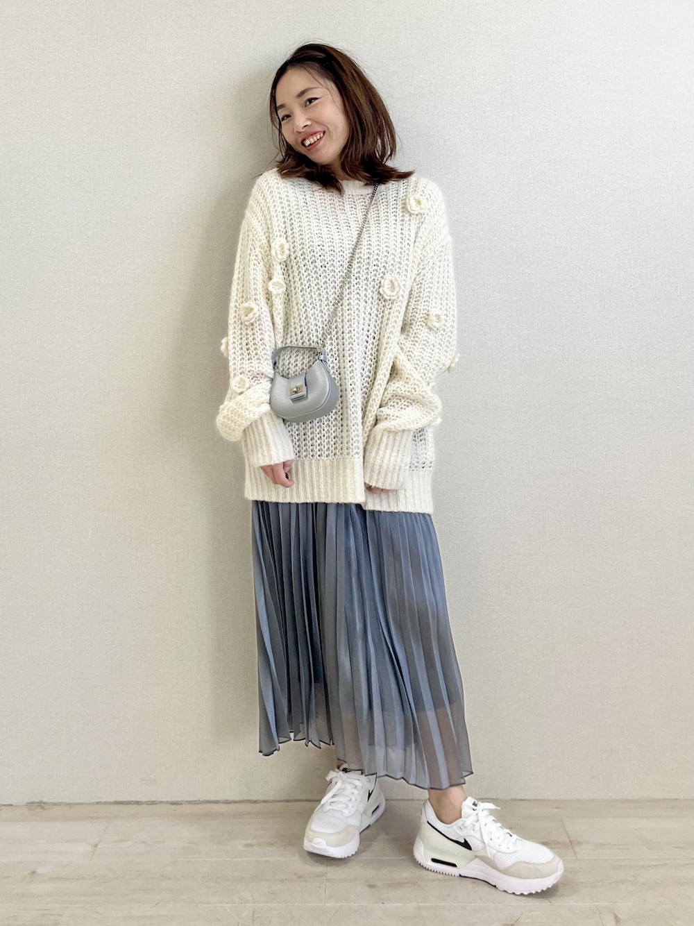 ホワイト系のニット/セーター、シルバー系のスカートを着用したレディースの冬コーディネートの1枚目の写真