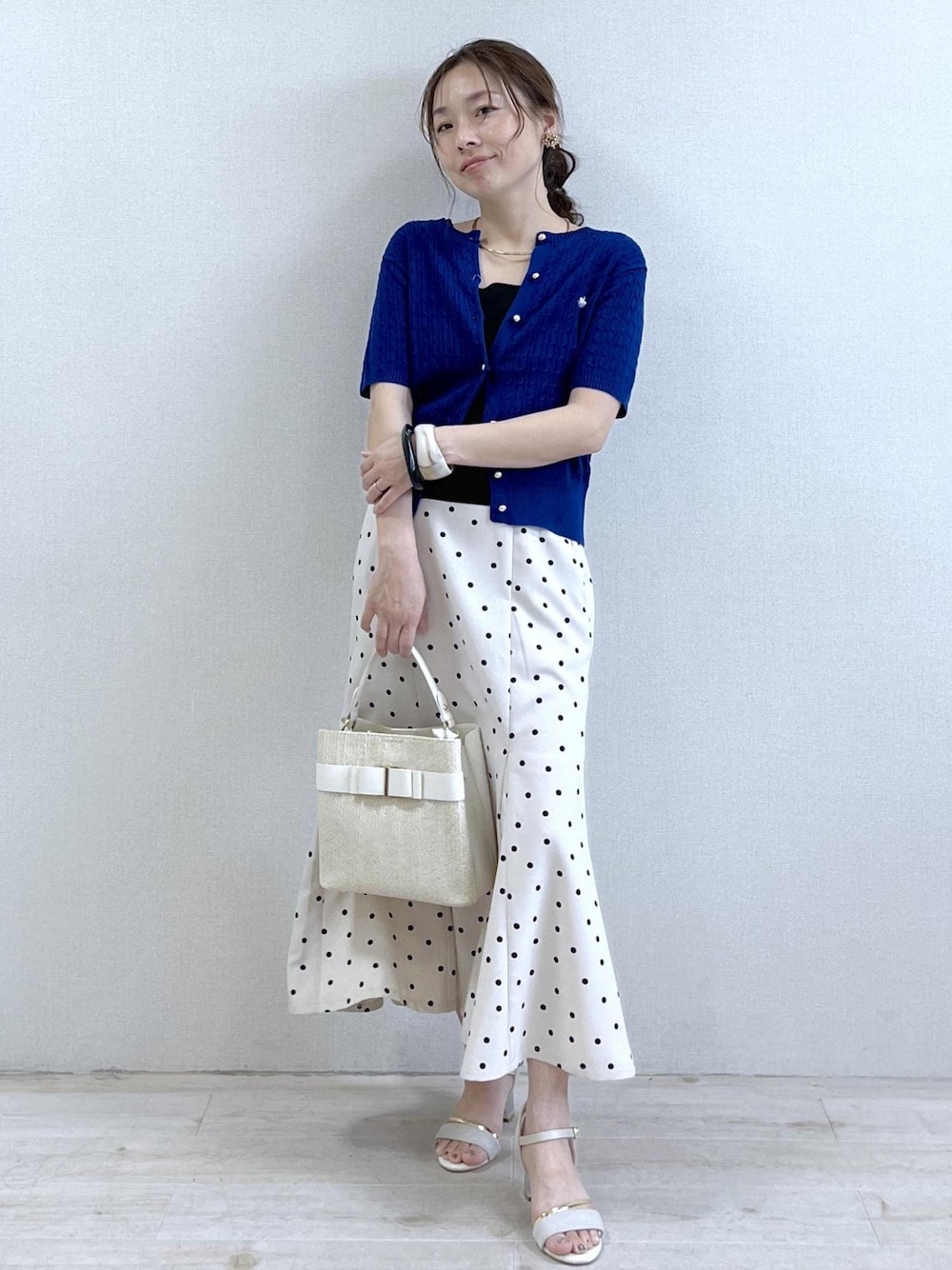 ホワイト系のサンダル、ホワイト系のスカート、ブラック系のキャミソールを着用したレディースの夏コーディネートの1枚目の写真