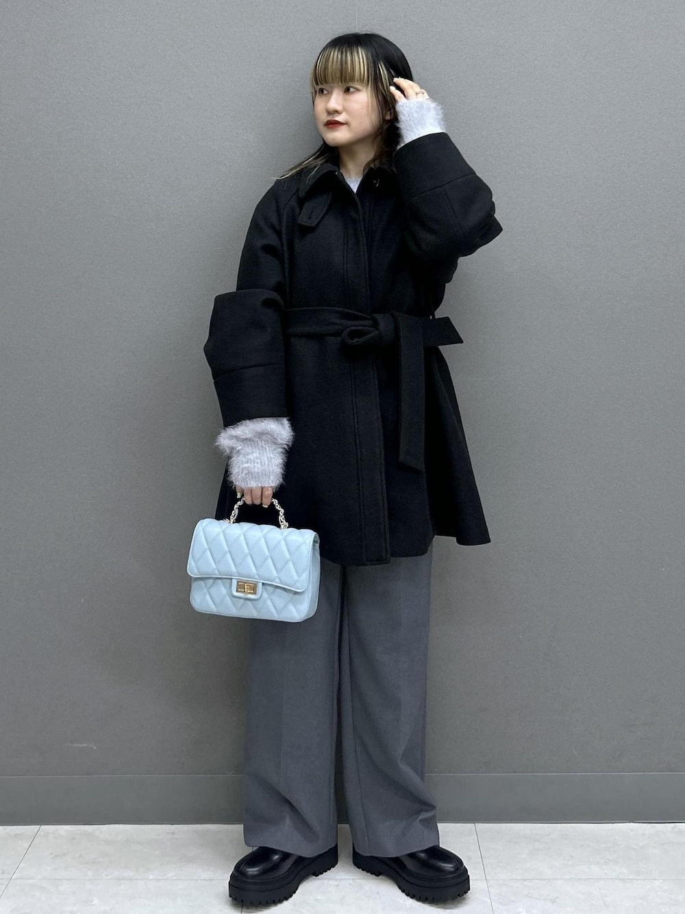 グレー系のスラックス、ブラック系のブーツ、ブラック系のチェスターコートを着用したレディースの秋コーディネートの1枚目の写真