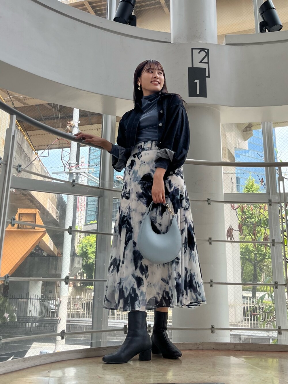 ブルー系のハンドバッグ、ブルー系のTシャツ/カットソー、ブラック系のデニムジャケットを着用したレディースの秋コーディネートの1枚目の写真