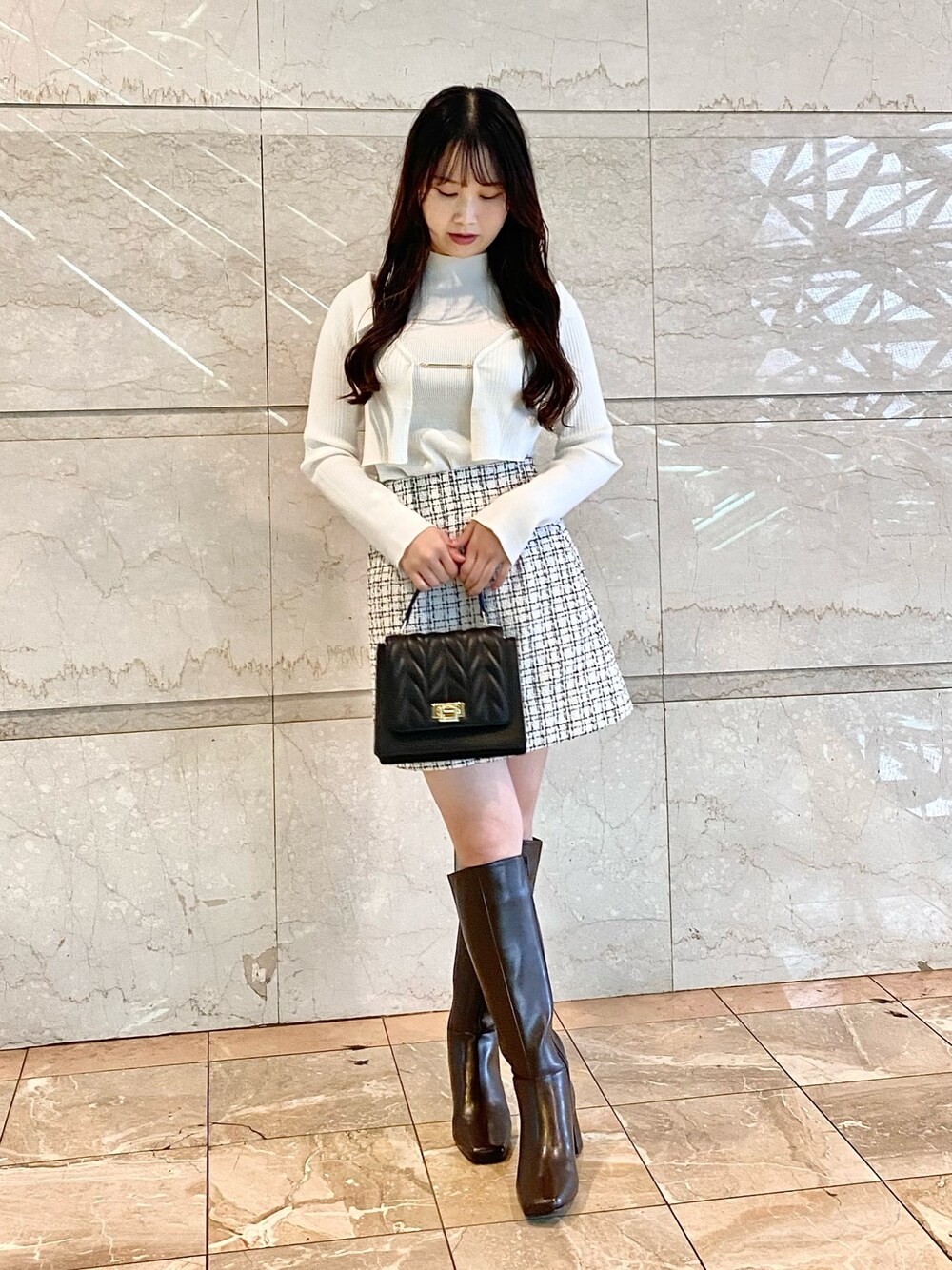 ホワイト系のニット/セーター、ホワイト系のスカート、ブラック系のショルダーバッグを着用したレディースの秋コーディネートの1枚目の写真