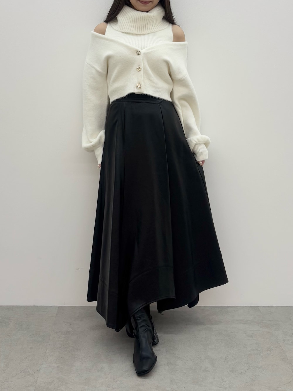 ホワイト系のニット/セーター、ブラック系のスカート、ブラック系のブーツを着用したレディースの冬コーディネートの1枚目の写真