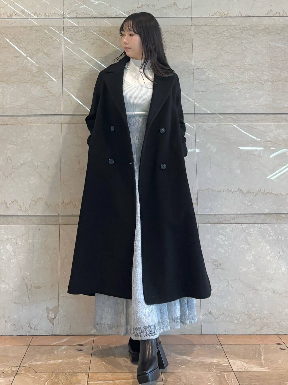 ブルー系のスカート、ブラック系のブーツ、ホワイト系のニット/セーターを着用したレディースの冬コーディネートの1枚目の写真