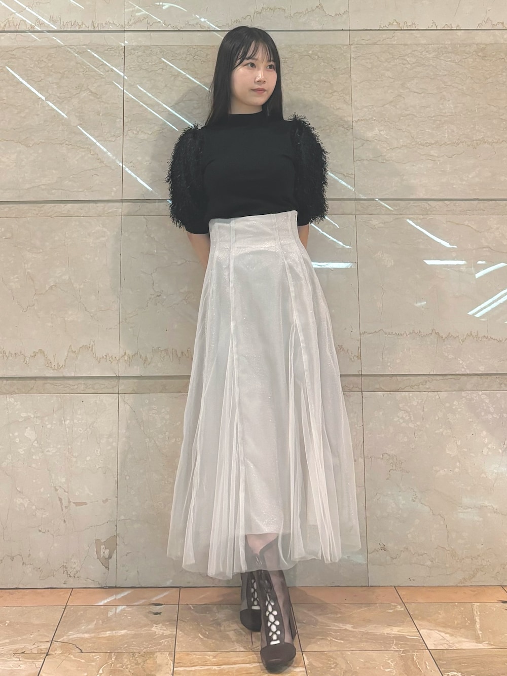 ホワイト系のスカート、ブラウン系のブーツ、ブラック系のニット/セーターを着用したレディースの秋コーディネートの1枚目の写真