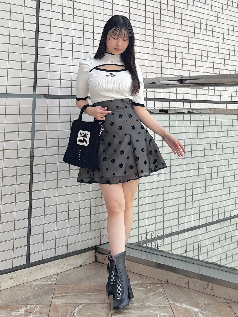 ブラック系のスカート、ブラック系のブーツ、ホワイト系のニット/セーターを着用したレディースの春コーディネートの1枚目の写真