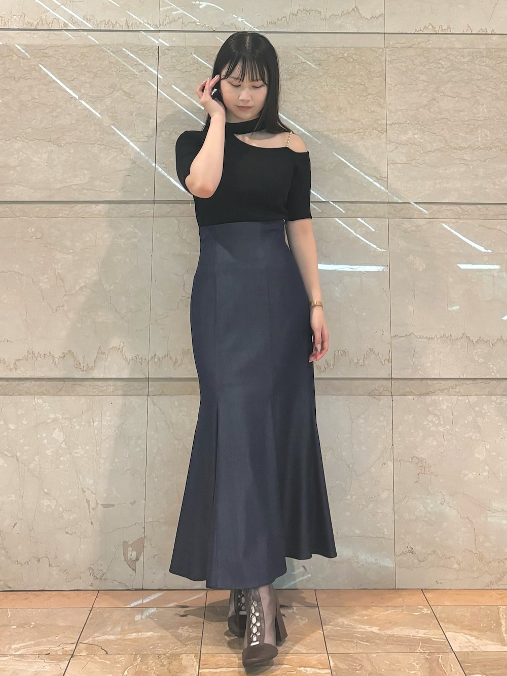 ブルー系のスカート、ブラウン系のブーツ、ブラック系のニット/セーターを着用したレディースの秋コーディネートの1枚目の写真