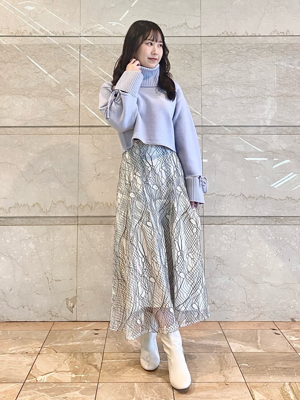 ホワイト系のスカート、ブルー系のニット/セーター、ホワイト系のブーツを着用したレディースの冬コーディネートの1枚目の写真
