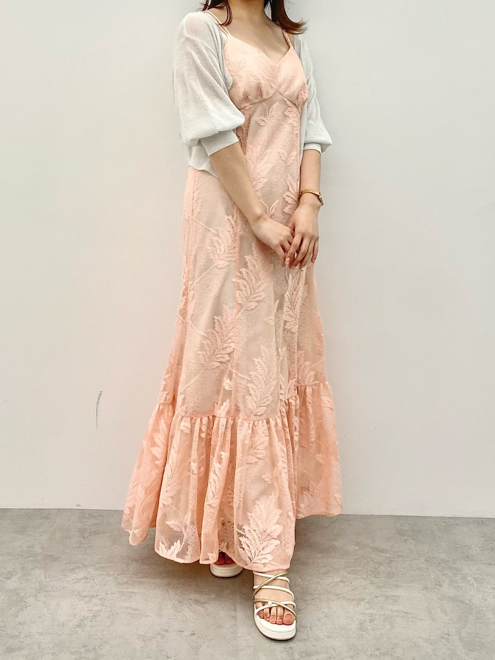 オレンジ系のワンピース、ホワイト系のサンダル、ホワイト系のカーディガン/ボレロを着用したレディースの春コーディネートの1枚目の写真