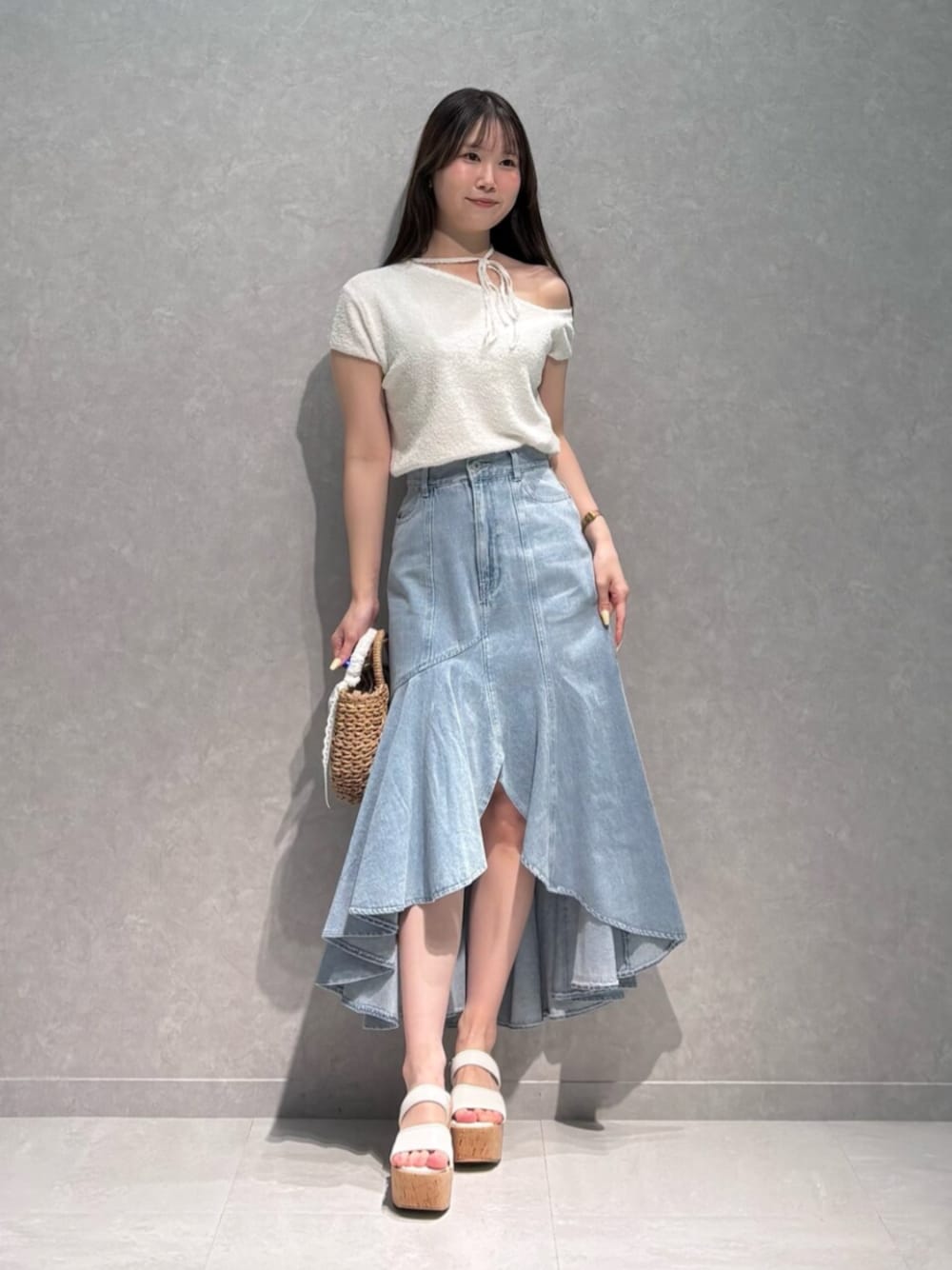 ホワイト系のサンダル、ベージュ系のハンドバッグ、ブルー系のスカートを着用したレディースの夏コーディネートの1枚目の写真