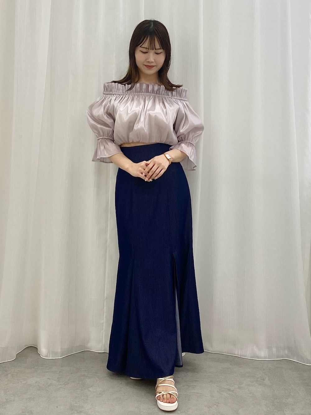 ブルー系のスカート、ホワイト系のサンダル、パープル系のシャツ/ブラウスを着用したレディースの春コーディネートの1枚目の写真