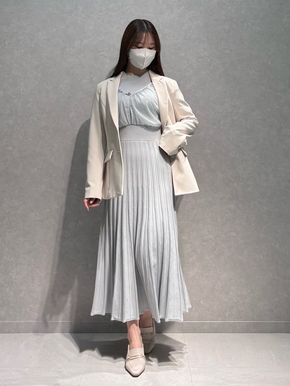 グレー系のワンピース、ホワイト系のテーラードジャケット、ホワイト系のパンプスを着用したレディースの春コーディネートの1枚目の写真