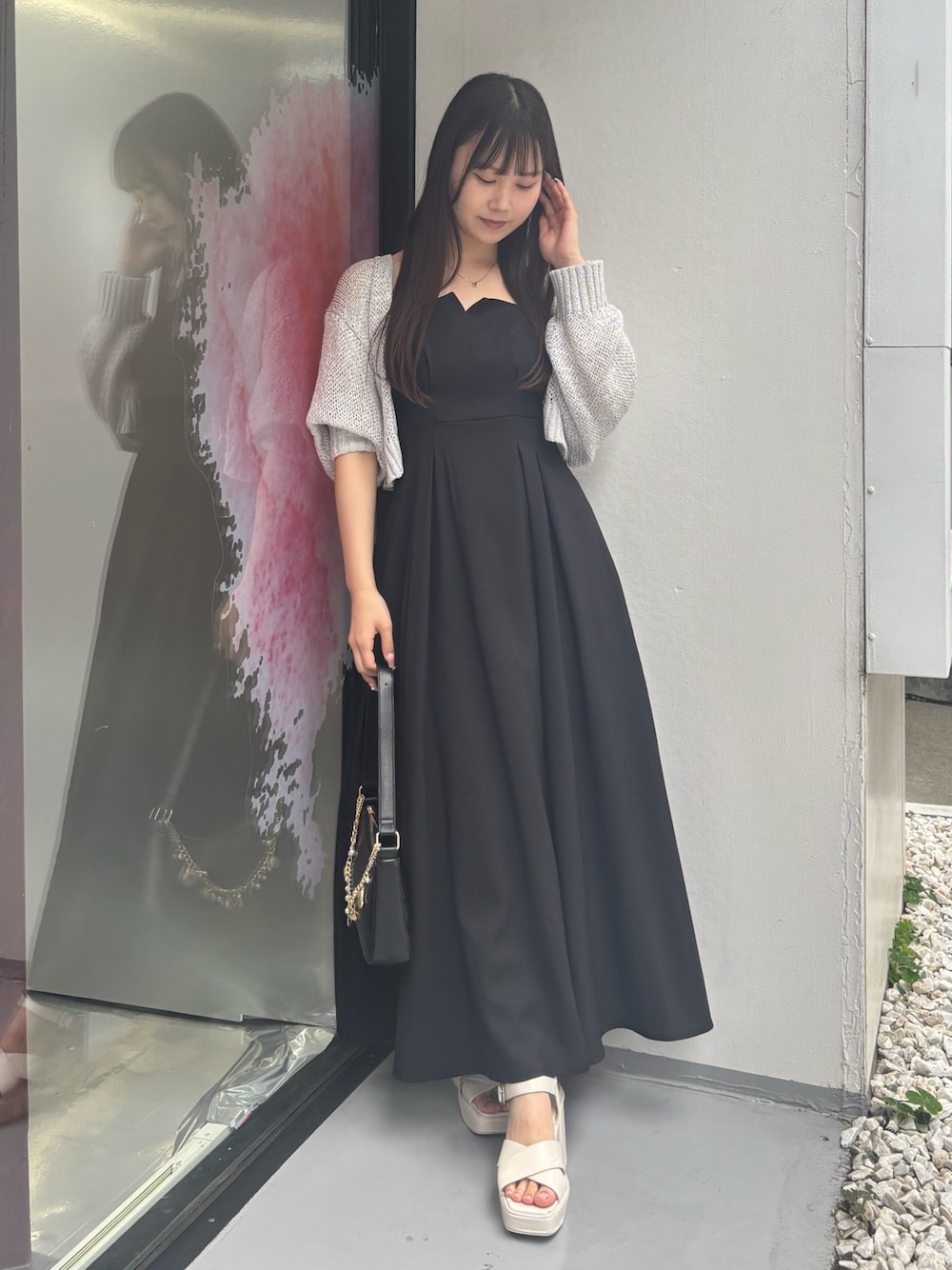 ブラック系のワンピース、ホワイト系のサンダル、ブラック系のハンドバッグを着用したレディースの夏コーディネートの1枚目の写真