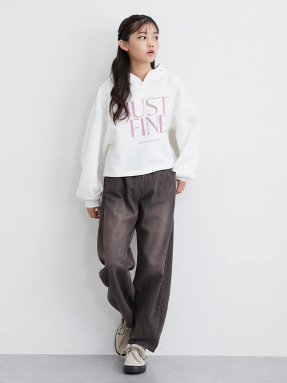 ホワイト系のパーカー、ブラウン系のデニムパンツを着用したキッズの秋コーディネートの1枚目の写真