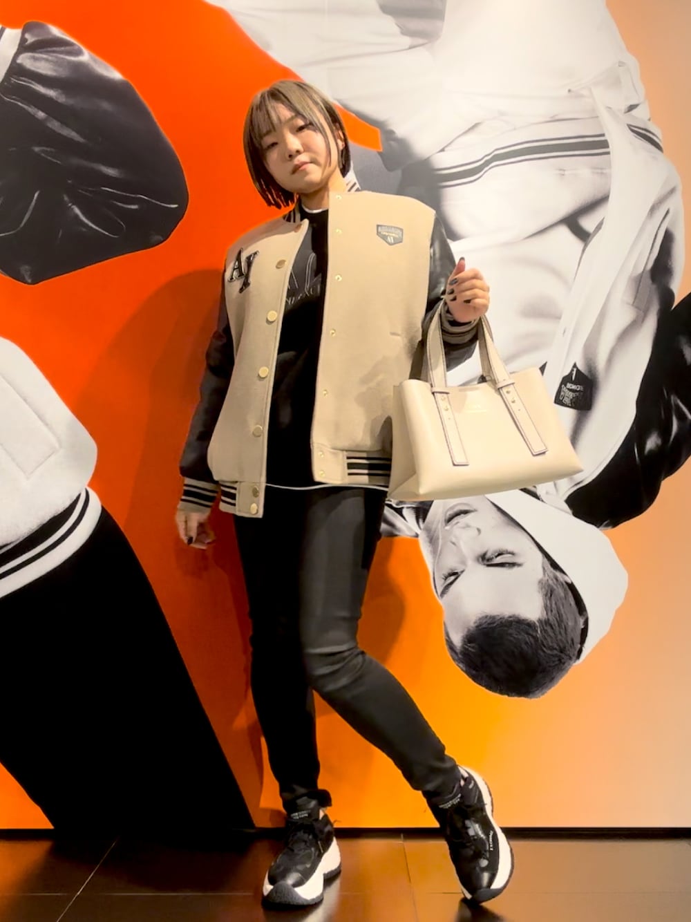 ベージュ系のトートバッグ、ブラック系のスウェット、ベージュ系のブルゾンを着用したレディースの秋コーディネートの1枚目の写真