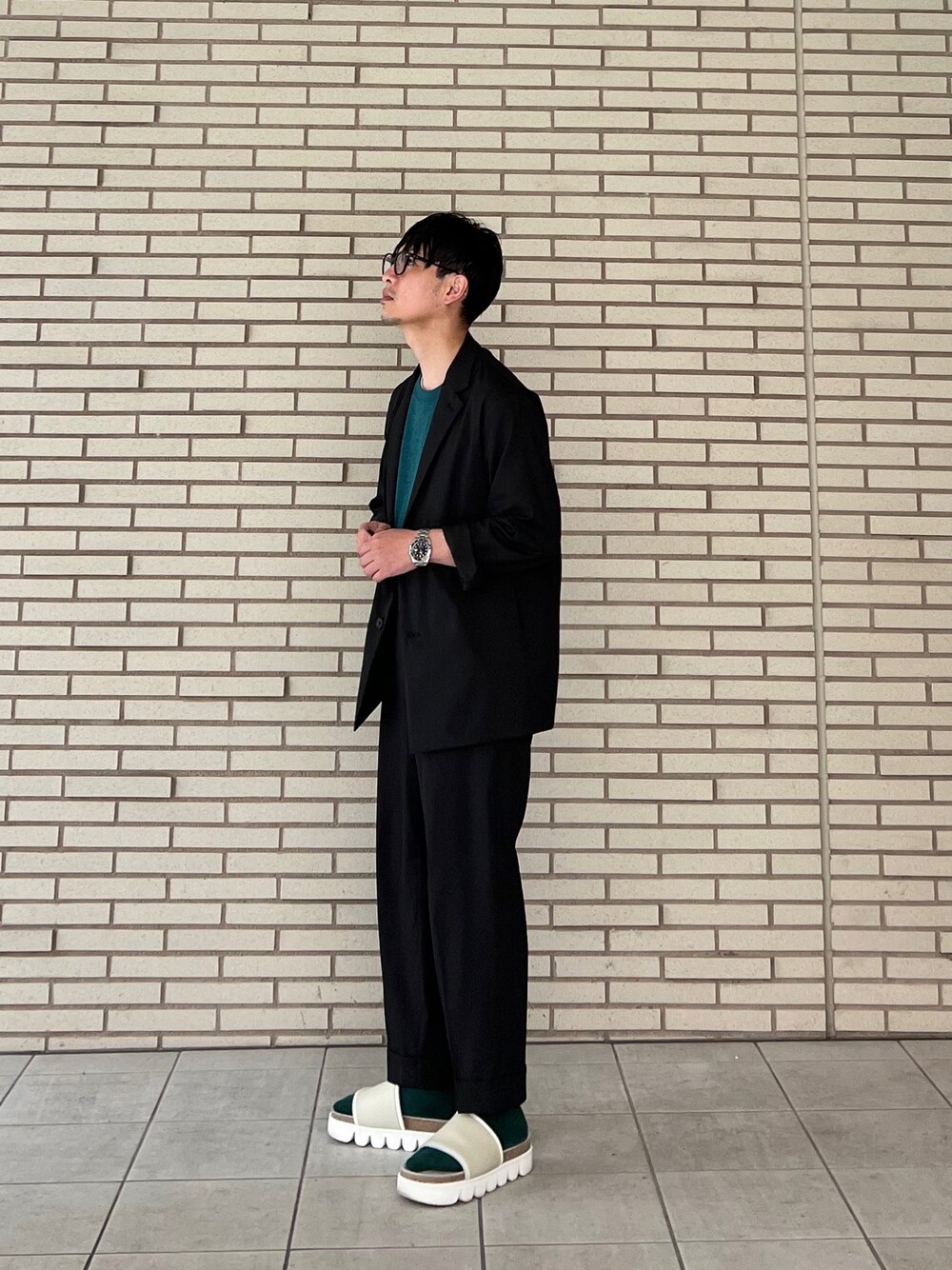 グリーン系のTシャツ/カットソー、ブラック系のセットアップ、ブラック系のスラックスを着用したメンズの春コーディネートの1枚目の写真