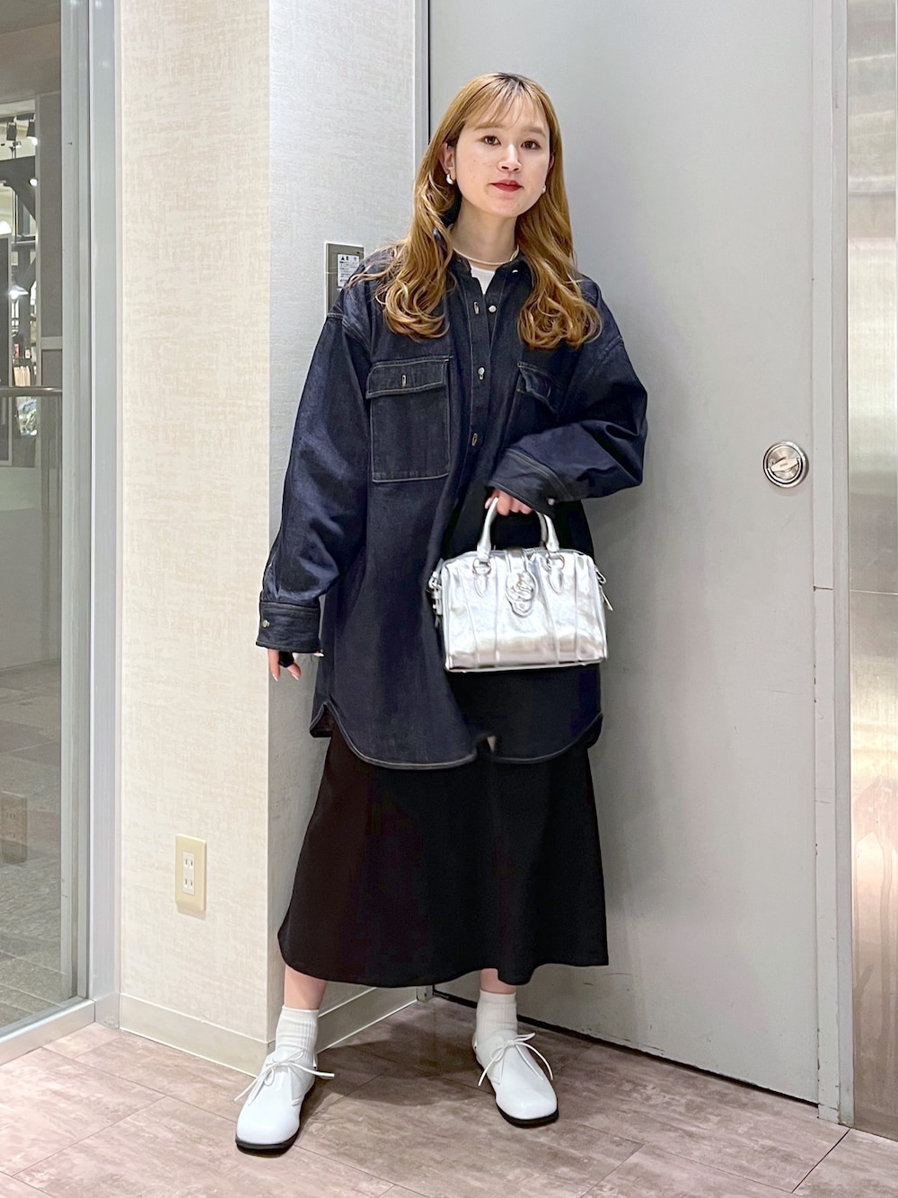 ブルー系のシャツ/ブラウス、ブラック系のスカート、シルバー系のショルダーバッグを着用したレディースの春コーディネートの2枚目の写真