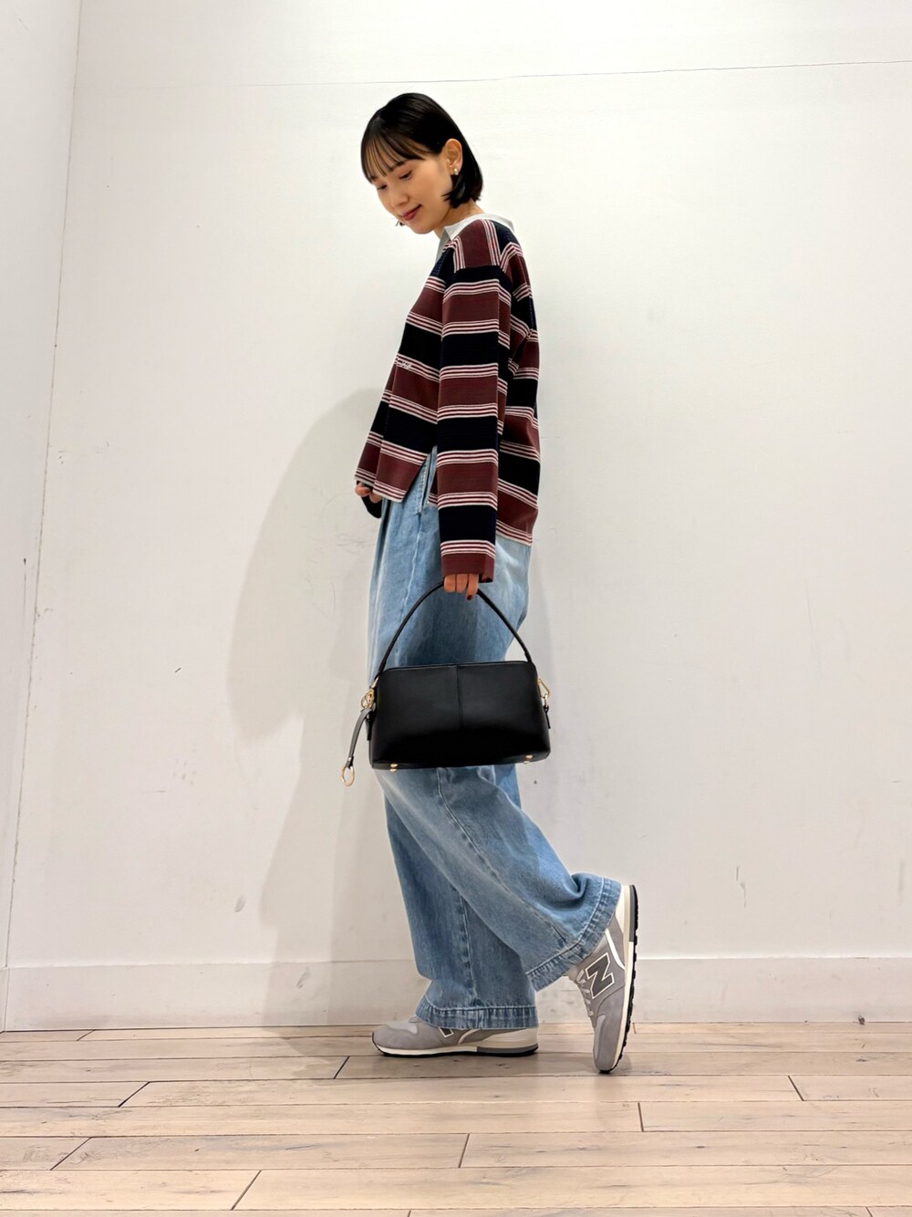ブルー系のニット/セーター、ブルー系のデニムパンツ、ブラック系のショルダーバッグを着用したレディースの秋コーディネートの1枚目の写真