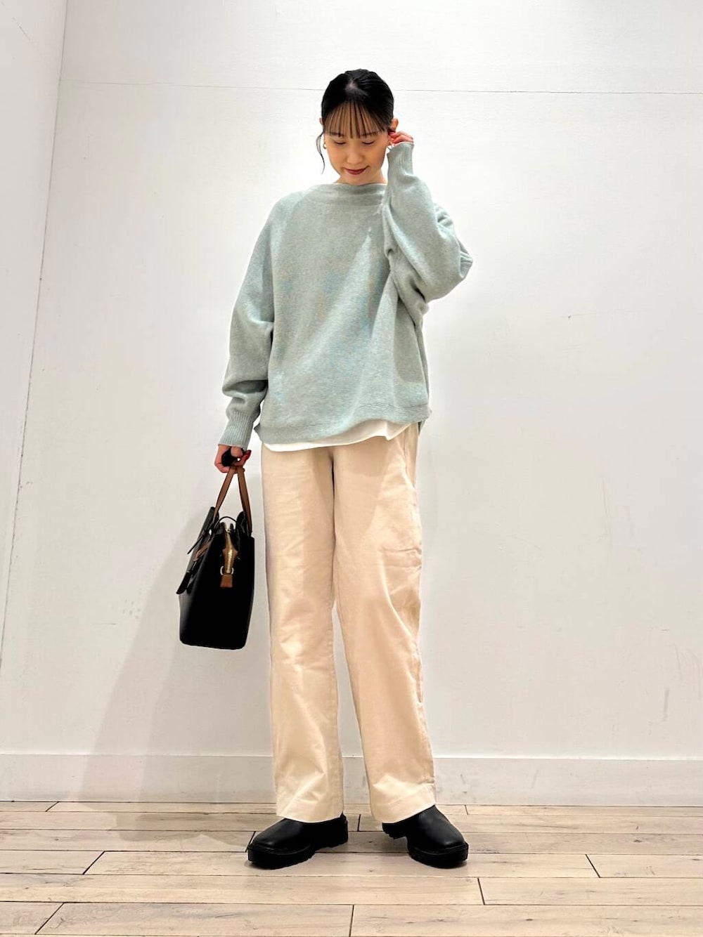 ブラック系のトートバッグ、グリーン系のニット/セーター、ブラック系のブーツを着用したレディースの冬コーディネートの1枚目の写真