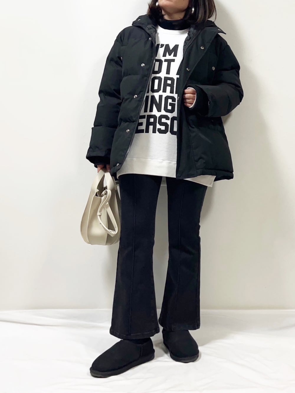 ブラック系のニット/セーター、ホワイト系のTシャツ/カットソー、ブラック系のダウンジャケット/コートを着用したレディースの冬コーディネートの1枚目の写真