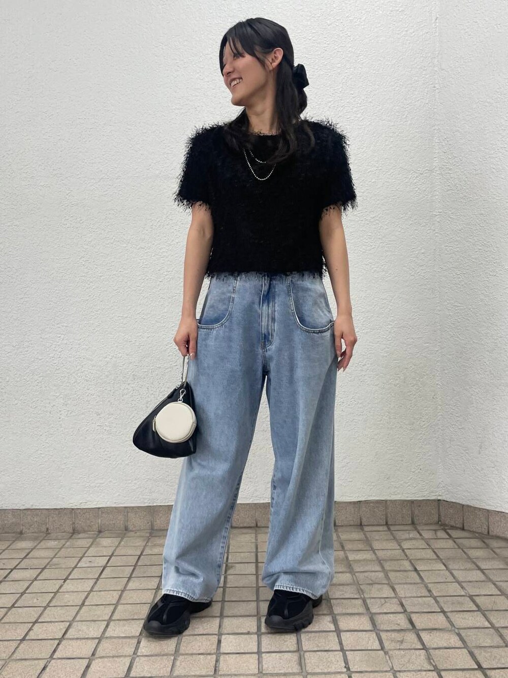 ブルー系のデニムパンツ、ブラック系のハンドバッグ、ブラック系のTシャツ/カットソーを着用したレディースの夏コーディネートの1枚目の写真