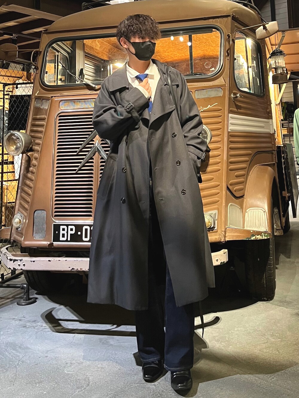 ホワイト系のシャツ/ブラウス、グレー系のトレンチコート、ブルー系のデニムパンツを着用したメンズの秋コーディネートの1枚目の写真