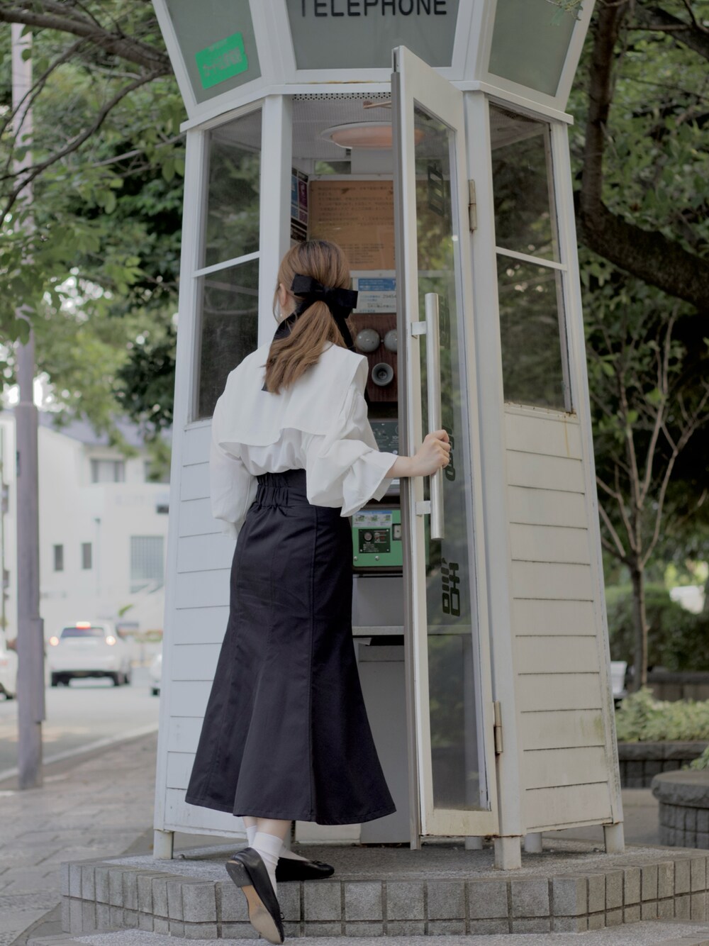 ブラック系のスカート、ブラック系のパンプス、ホワイト系のシャツ/ブラウスを着用したレディースの夏コーディネートの1枚目の写真