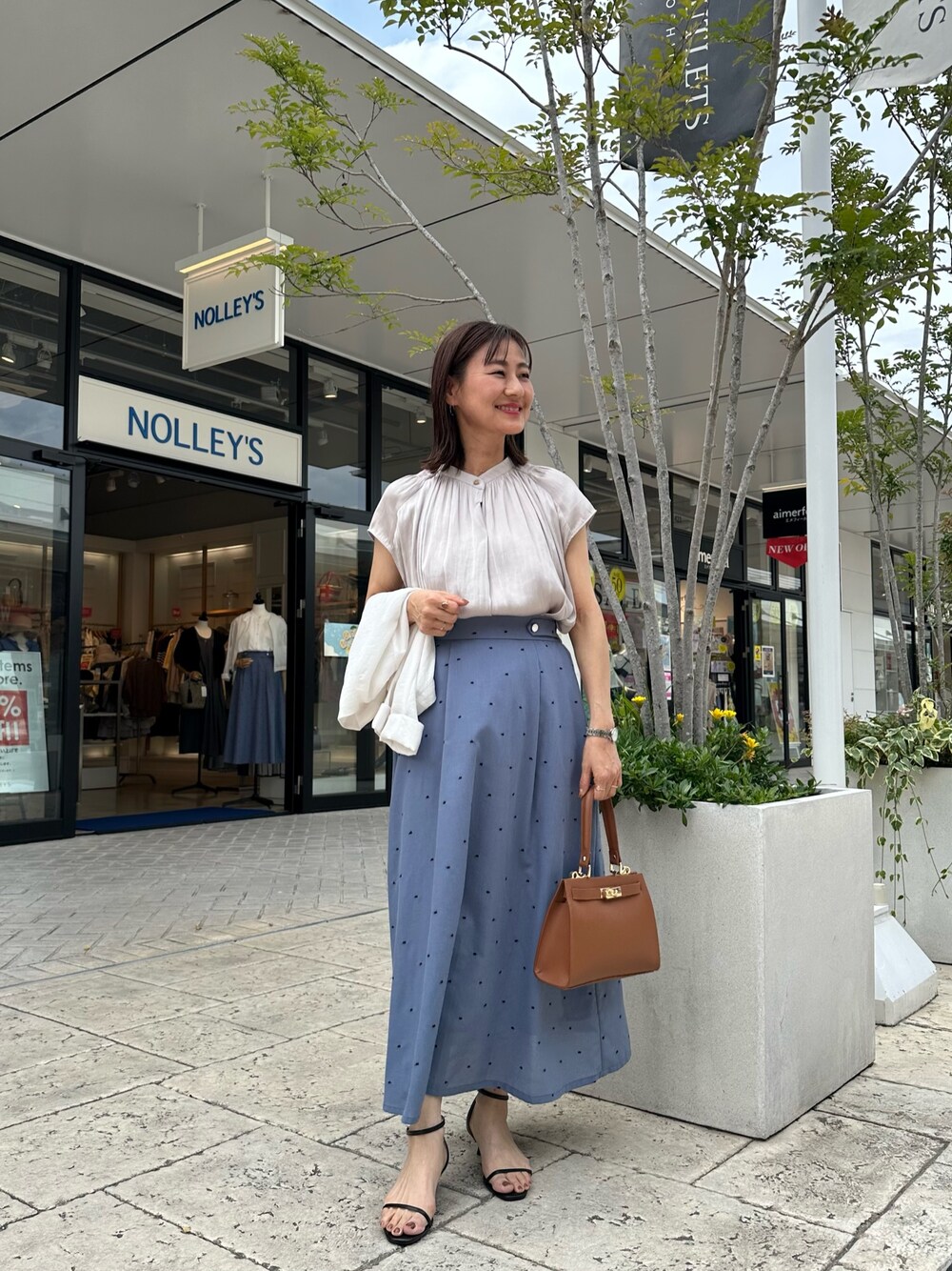 ベージュ系のシャツ/ブラウス、ブルー系のスカート、イエロー系のショルダーバッグを着用したレディースの春コーディネートの1枚目の写真
