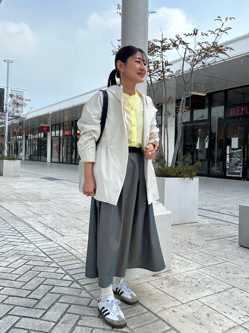 ホワイト系のブルゾン、イエロー系のシャツ/ブラウス、グリーン系のスカートを着用したレディースの冬コーディネートの1枚目の写真