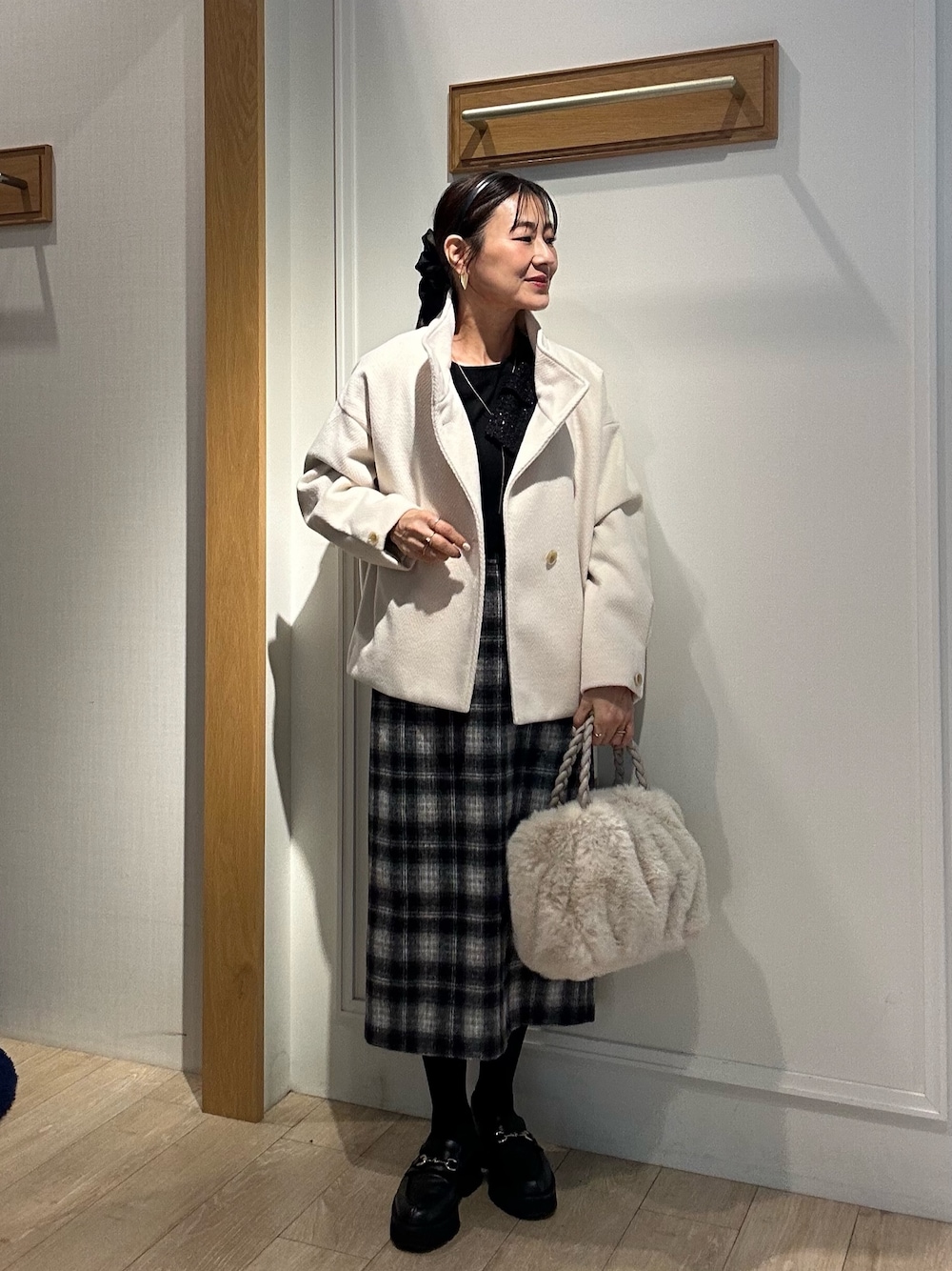 ホワイト系のトートバッグ、ホワイト系のテーラードジャケット、ブラック系のニット/セーターを着用したレディースの冬コーディネートの1枚目の写真