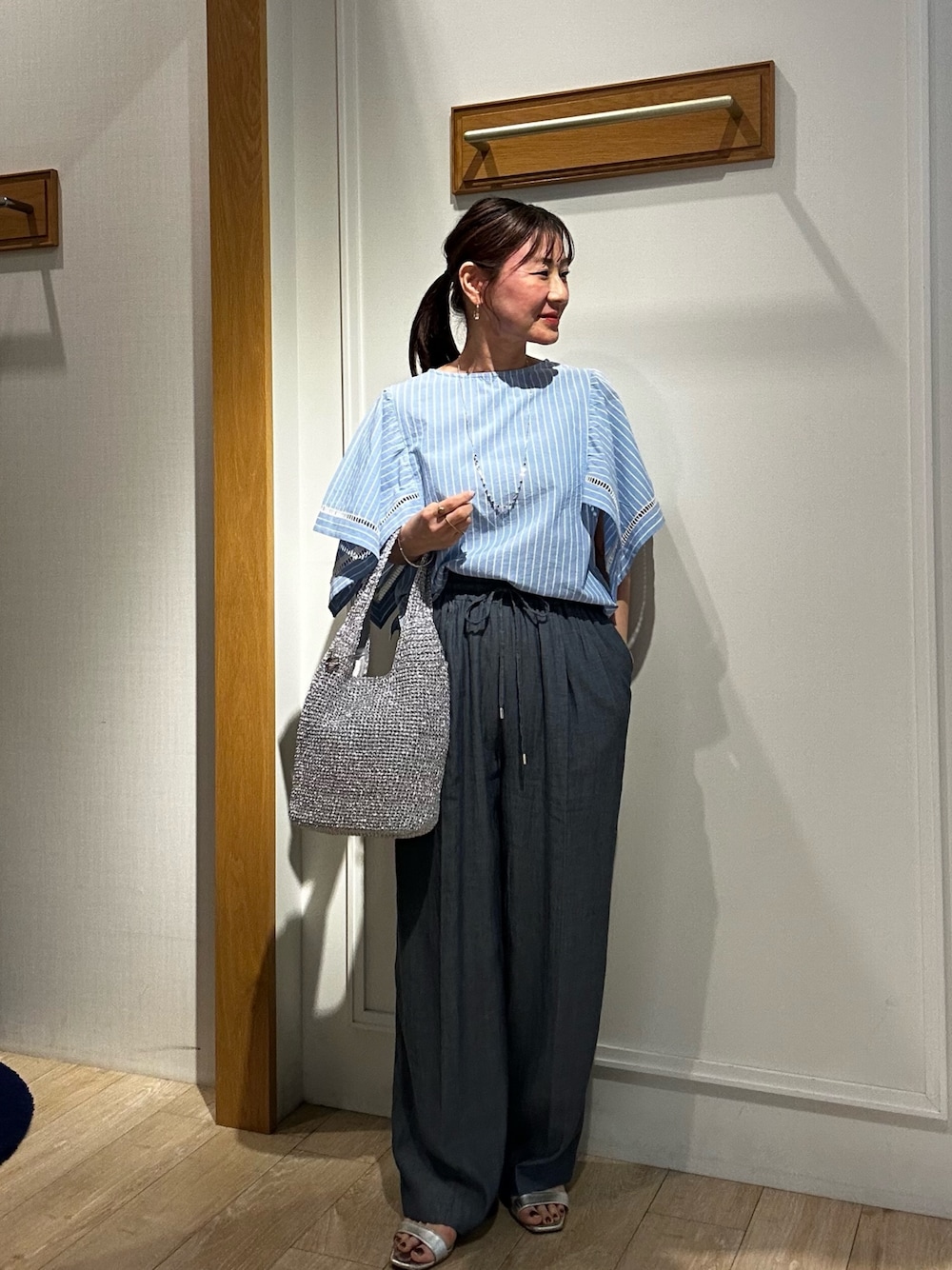 ブルー系のシャツ/ブラウス、ブルー系のデニムパンツ、シルバー系のトートバッグを着用したレディースの春コーディネートの1枚目の写真