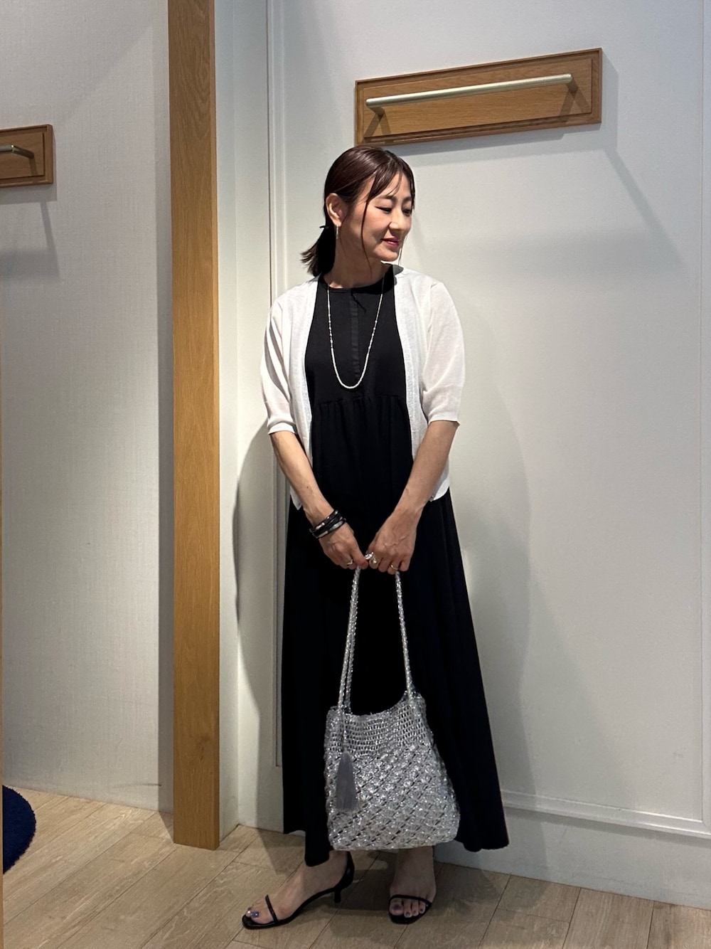 ホワイト系のニット/セーター、ブラック系のワンピース、ブラック系のサンダルを着用したレディースの夏コーディネートの1枚目の写真