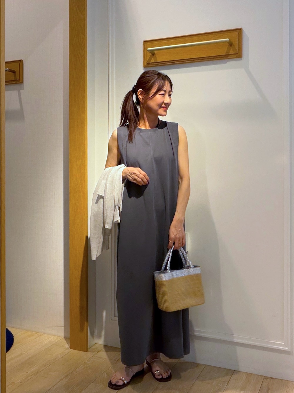 グレー系のワンピース、ベージュ系のカーディガン/ボレロ、ブラック系のネックレスを着用したレディースの夏コーディネートの1枚目の写真