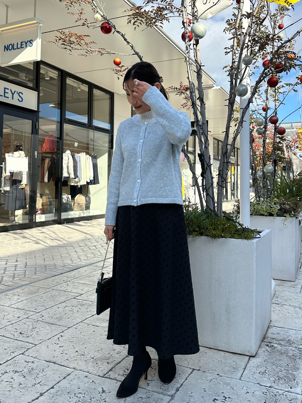 グレー系のニット/セーター、ブラック系のショルダーバッグを着用したレディースの冬コーディネートの1枚目の写真
