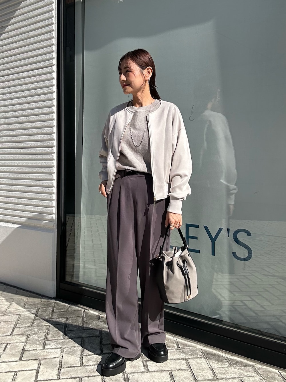 グレー系のその他パンツ、グレー系のニット/セーター、ベージュ系のブルゾンを着用したレディースの秋コーディネートの1枚目の写真