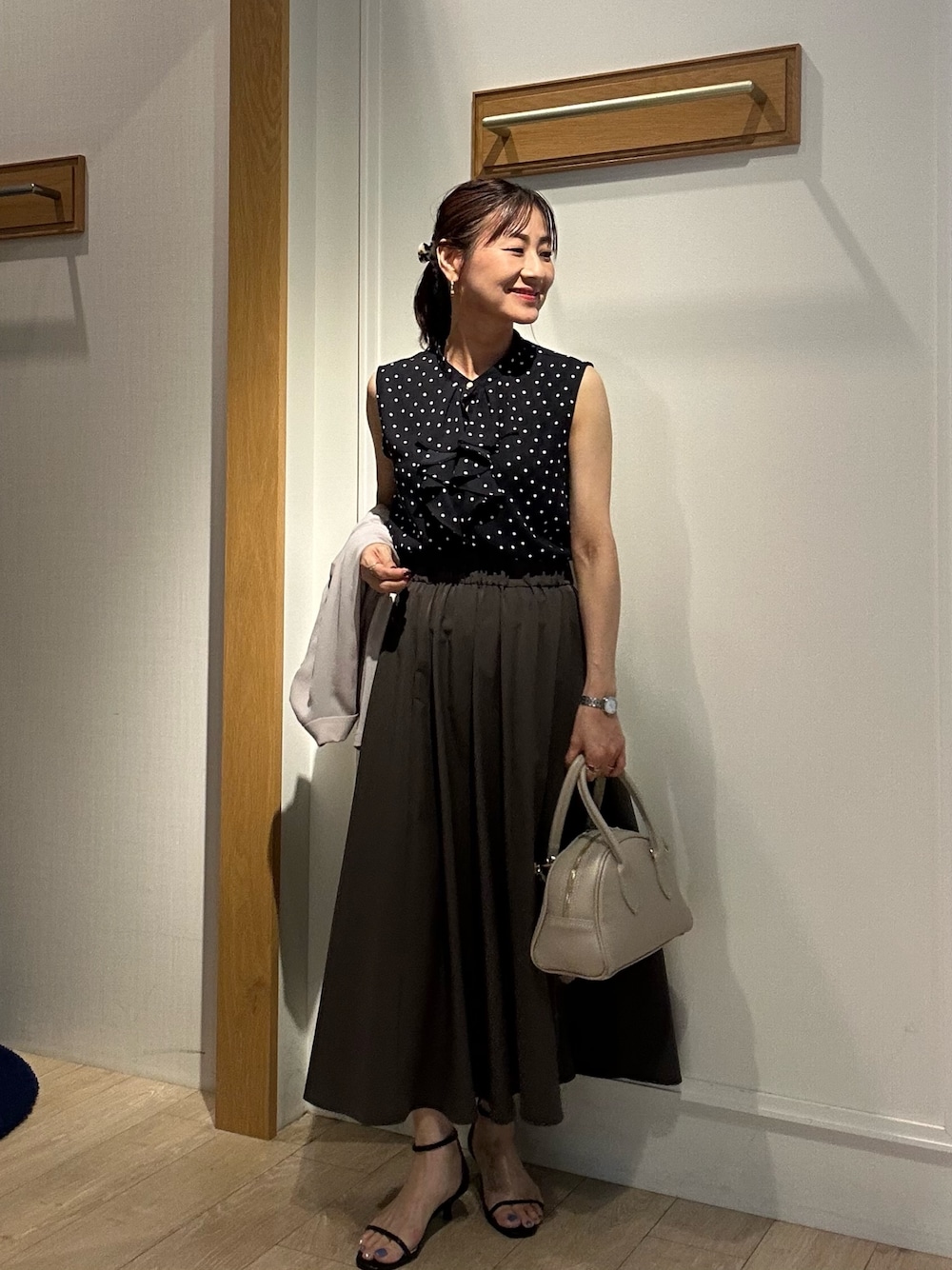 ブラック系のシャツ/ブラウス、グレー系のスカート、ベージュ系のボストンバッグを着用したレディースの夏コーディネートの1枚目の写真