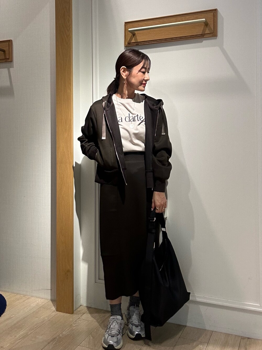 ブラウン系のパーカー、ブラウン系のスカート、ブラック系のショルダーバッグを着用したレディースの秋コーディネートの1枚目の写真