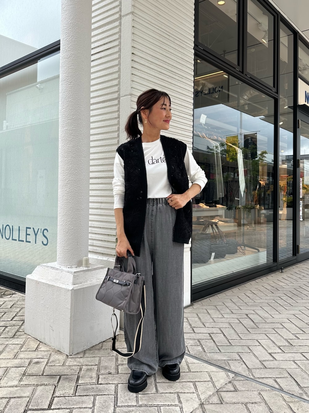 グレー系のデニムパンツ、ブラック系のニット/セーター、グレー系のトートバッグを着用したレディースの秋コーディネートの1枚目の写真