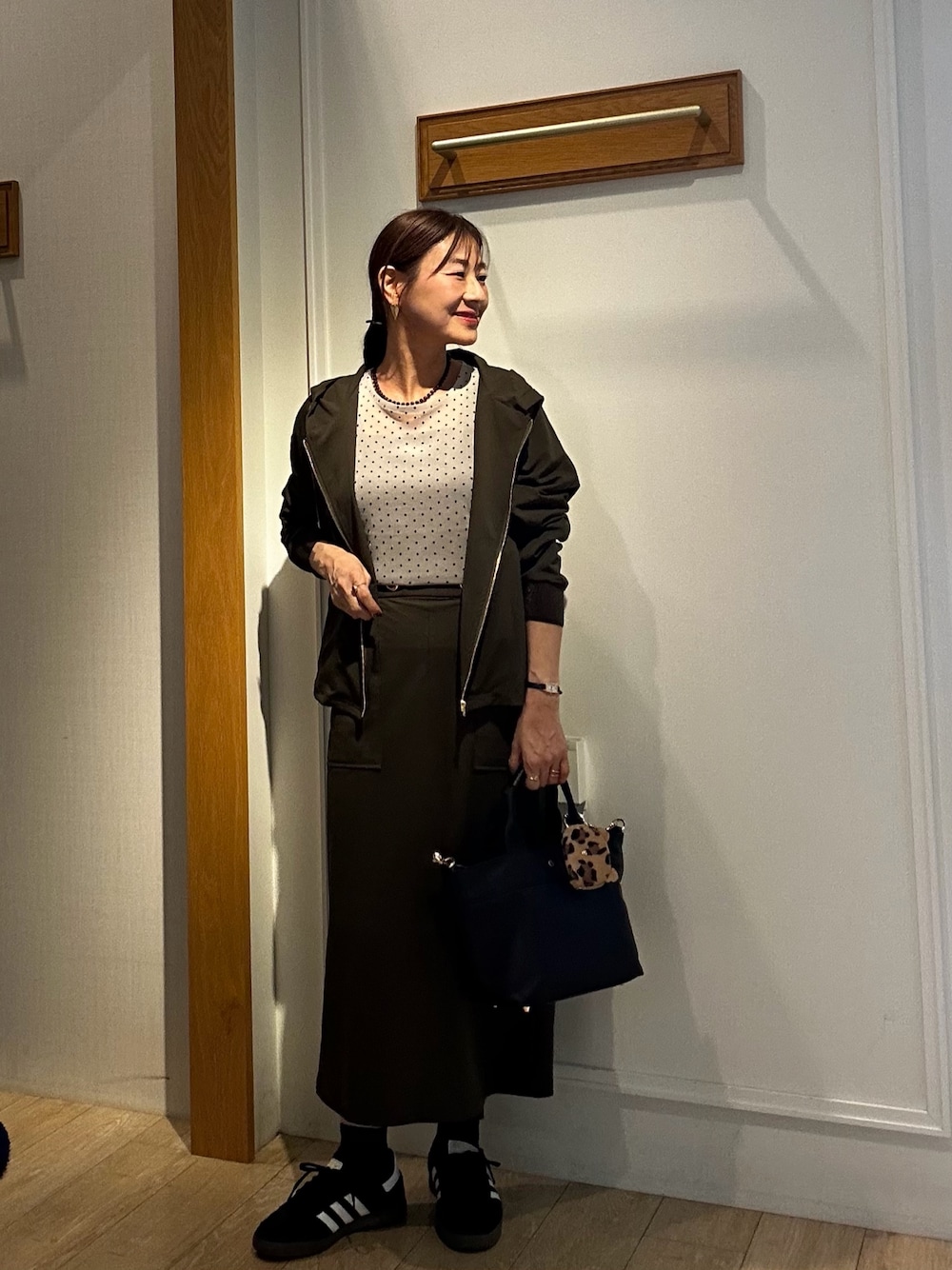 グリーン系のブルゾン、ベージュ系のTシャツ/カットソー、ブラック系のトートバッグを着用したレディースの秋コーディネートの1枚目の写真
