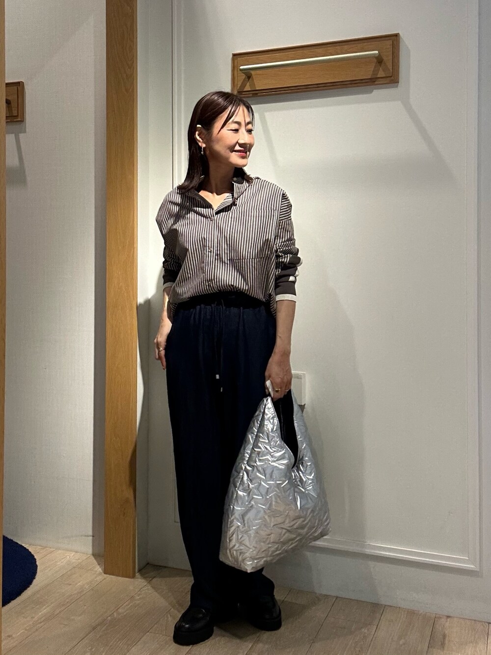 ブラウン系のシャツ/ブラウス、ブルー系のデニムパンツ、シルバー系のトートバッグを着用したレディースの秋コーディネートの1枚目の写真