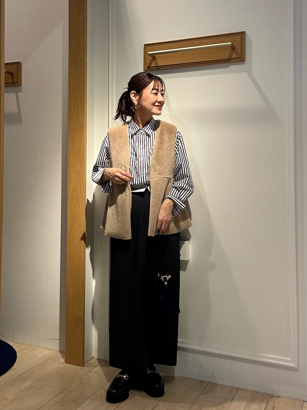 グレー系のスカート、ブラック系のシャツ/ブラウス、イエロー系のブルゾンを着用したレディースの秋コーディネートの1枚目の写真