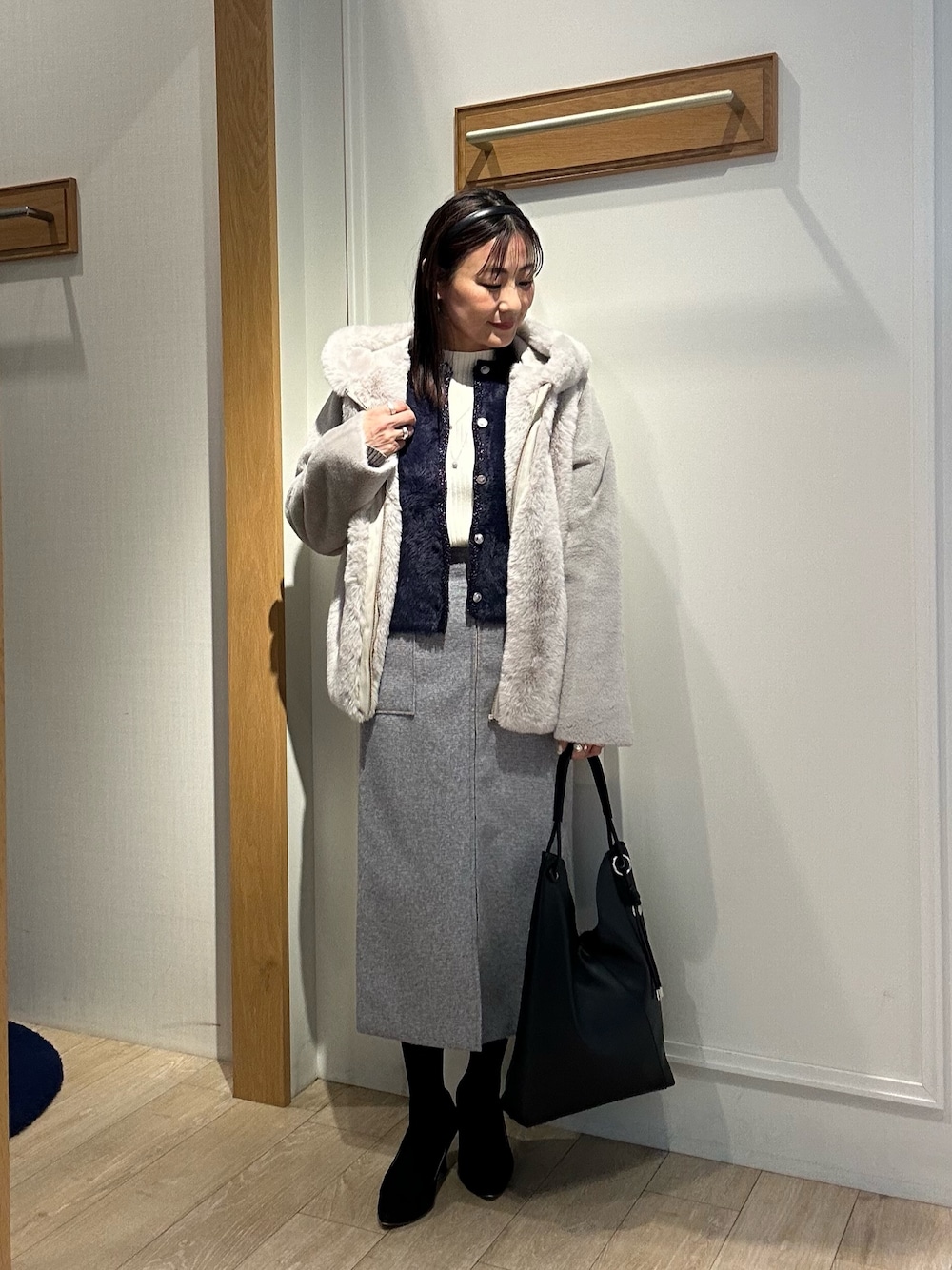 ベージュ系のムートンコート、ブルー系のニット/セーター、ホワイト系のニット/セーターを着用したレディースの冬コーディネートの1枚目の写真