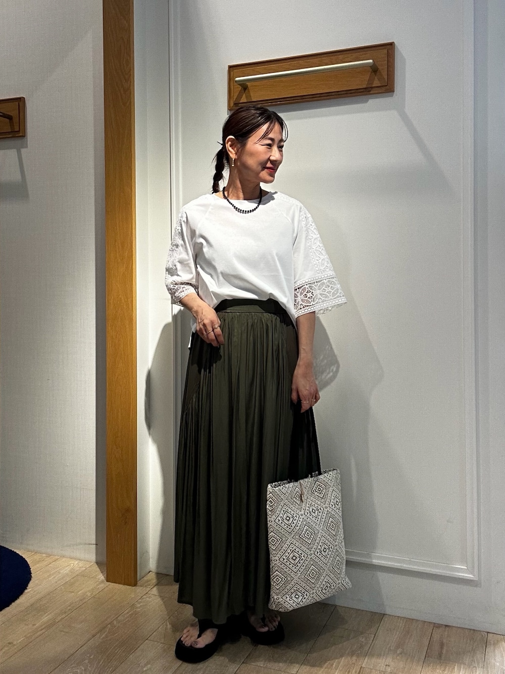 ホワイト系のTシャツ/カットソー、ブラック系のトートバッグ、グリーン系のスカートを着用したレディースの夏コーディネートの1枚目の写真