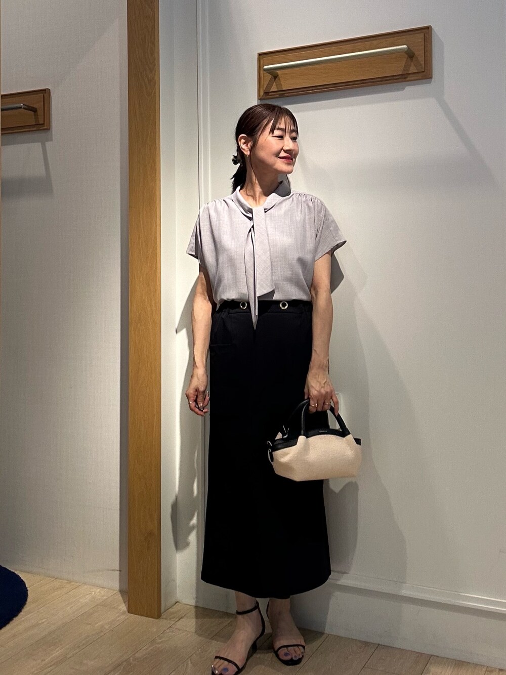 グレー系のシャツ/ブラウス、ブラック系のスカート、ブラック系のバックパック/リュックを着用したレディースの夏コーディネートの1枚目の写真