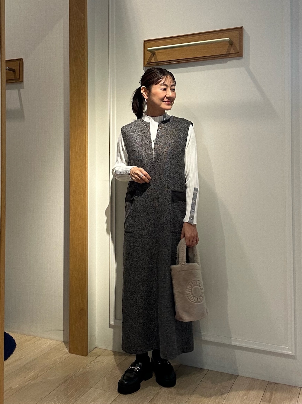 グレー系のワンピース、ホワイト系のニット/セーター、ベージュ系のトートバッグを着用したレディースの秋コーディネートの1枚目の写真