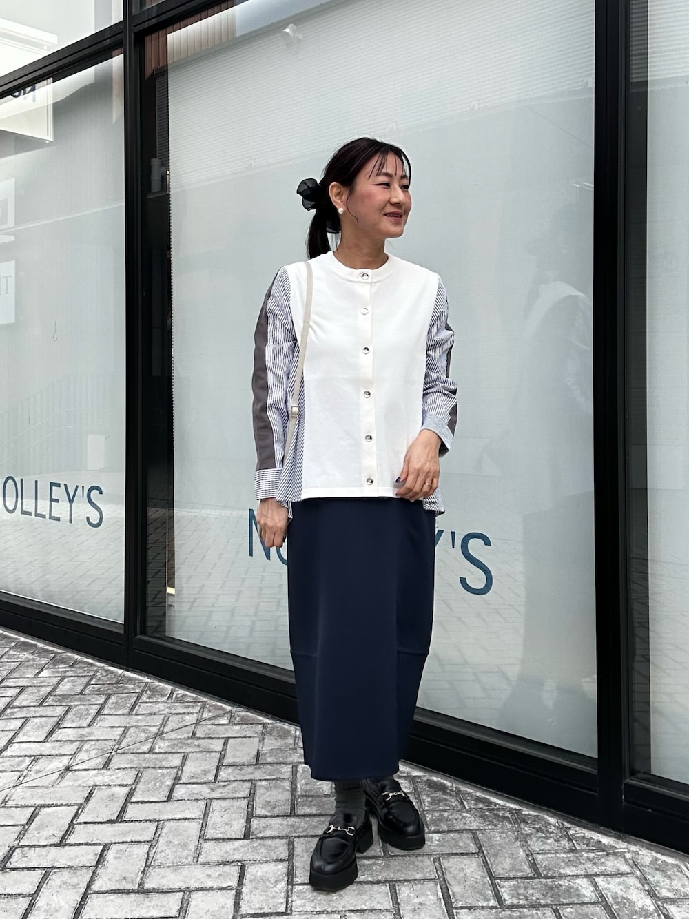 ブルー系のスカート、ホワイト系のニット/セーター、ホワイト系のショルダーバッグを着用したレディースの冬コーディネートの1枚目の写真